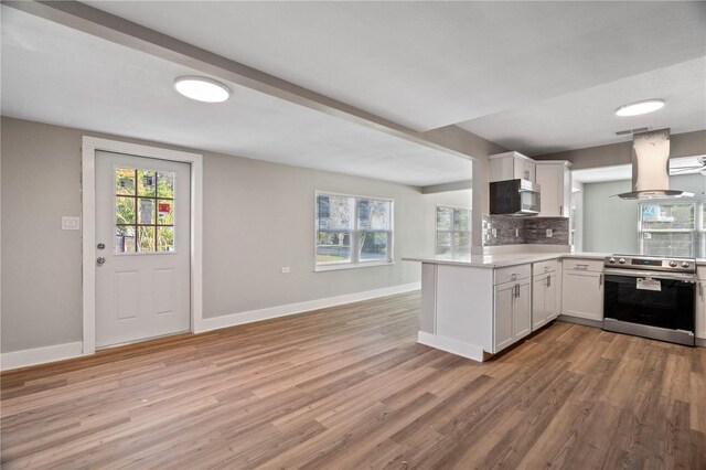 kitchen featuring kitchen peninsula, island exhaust hood, white cabinets, light hardwood / wood-style flooring, and stainless steel appliances