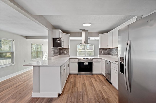 kitchen featuring island exhaust hood, stainless steel appliances, kitchen peninsula, and white cabinets