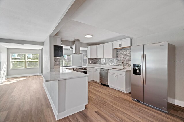 kitchen with white cabinetry, kitchen peninsula, stainless steel appliances, and extractor fan