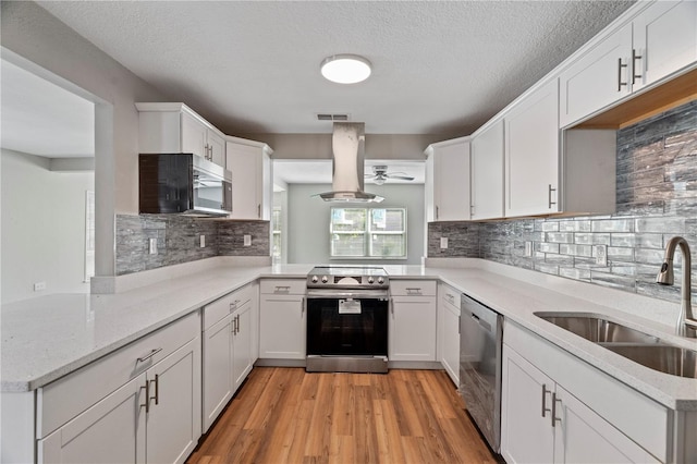 kitchen with kitchen peninsula, white cabinetry, island range hood, sink, and stainless steel appliances