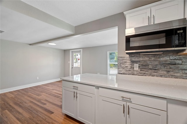 kitchen featuring light hardwood / wood-style floors, tasteful backsplash, light stone countertops, and white cabinets