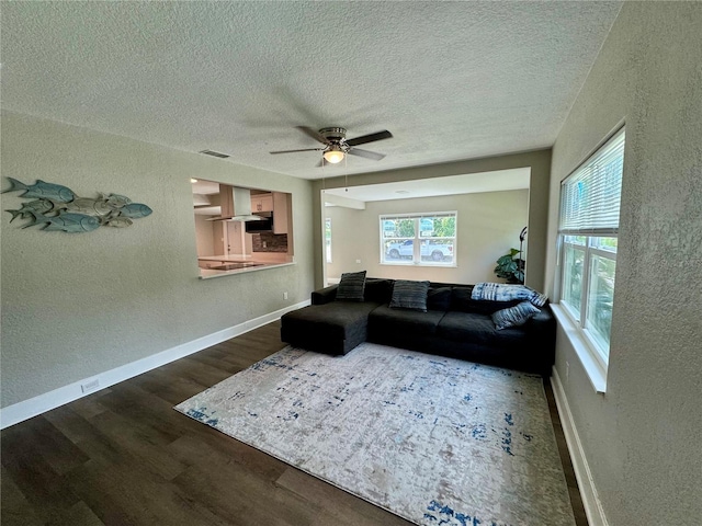 living room with a textured ceiling, dark wood-type flooring, and ceiling fan