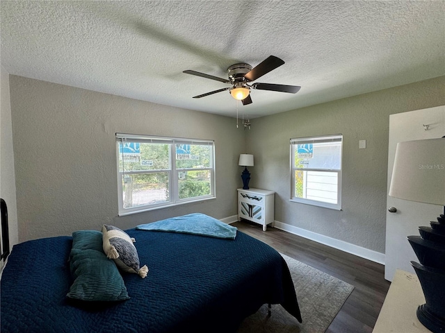 bedroom with ceiling fan, a textured ceiling, and dark hardwood / wood-style floors