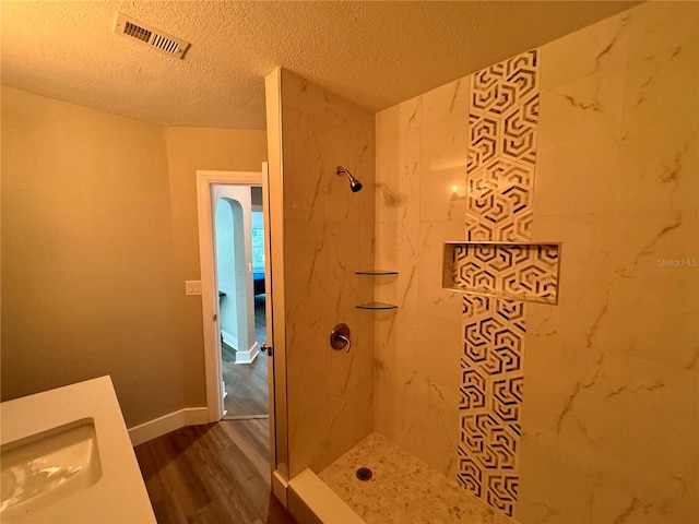 bathroom featuring hardwood / wood-style flooring, a textured ceiling, sink, and tiled shower