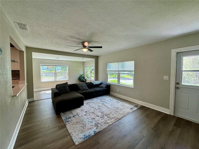 living room with ceiling fan, a textured ceiling, and dark hardwood / wood-style flooring