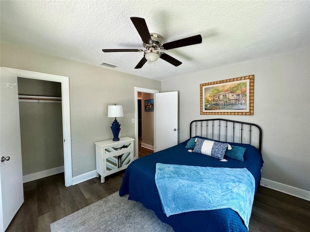 bedroom with dark wood-type flooring, ceiling fan, a closet, and a textured ceiling