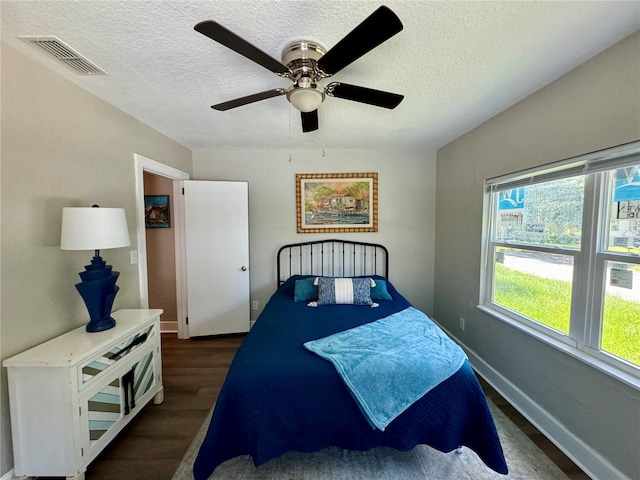 bedroom with dark wood-type flooring, ceiling fan, and a textured ceiling