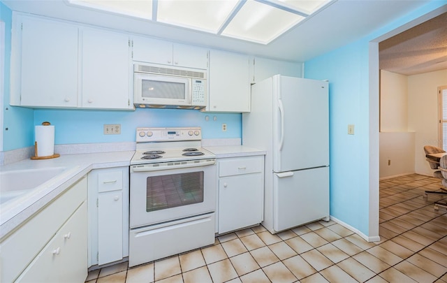 kitchen with white appliances, white cabinets, light tile patterned flooring, and light countertops