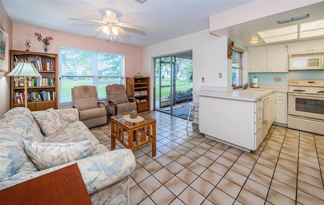 kitchen featuring open floor plan, light countertops, light tile patterned floors, white appliances, and a sink