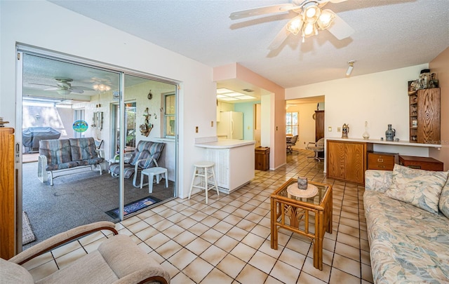 living area featuring plenty of natural light, light tile patterned floors, and ceiling fan