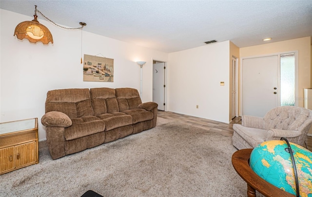 living room with carpet flooring, a textured ceiling, and visible vents