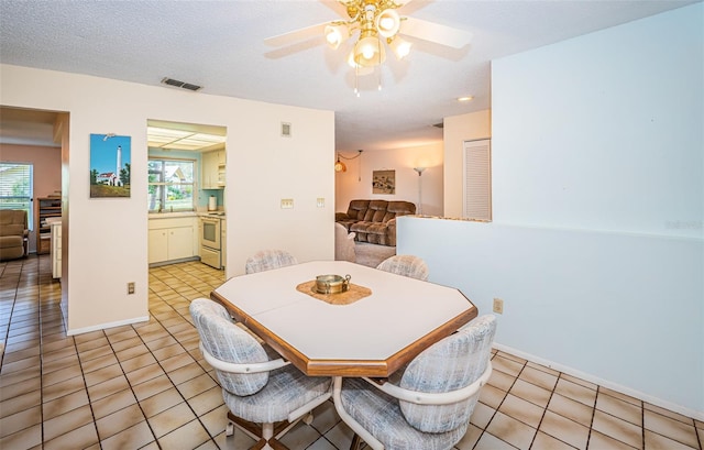 dining room with a wealth of natural light, visible vents, ceiling fan, and light tile patterned floors