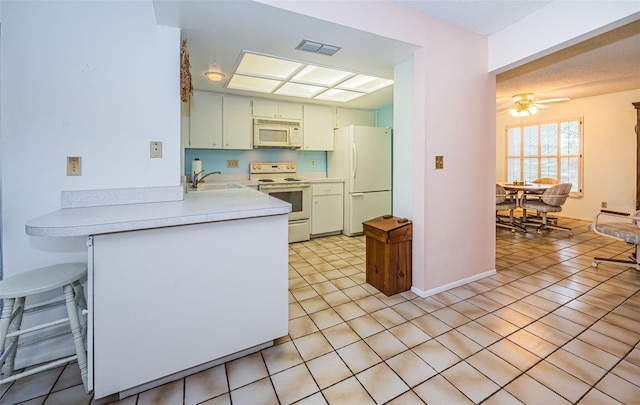 kitchen featuring white appliances, visible vents, a peninsula, ceiling fan, and light countertops