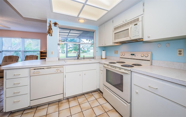 kitchen featuring white appliances, a peninsula, a sink, light countertops, and white cabinets