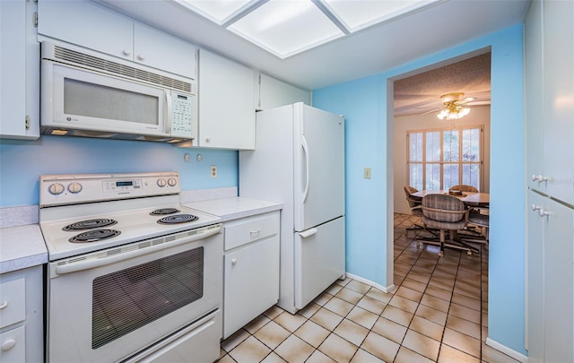 kitchen featuring white appliances, light tile patterned flooring, white cabinets, and light countertops