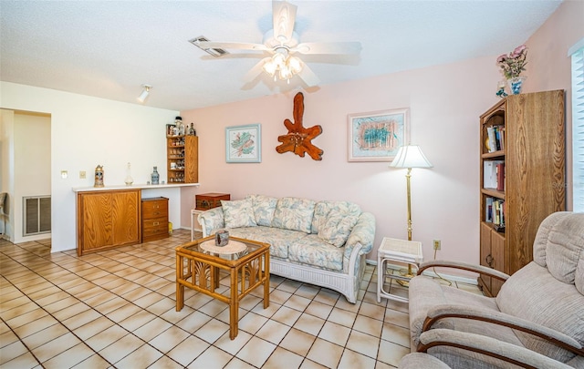 living room featuring light tile patterned floors, visible vents, and a ceiling fan