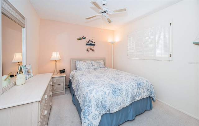 bedroom featuring baseboards, light colored carpet, and a ceiling fan