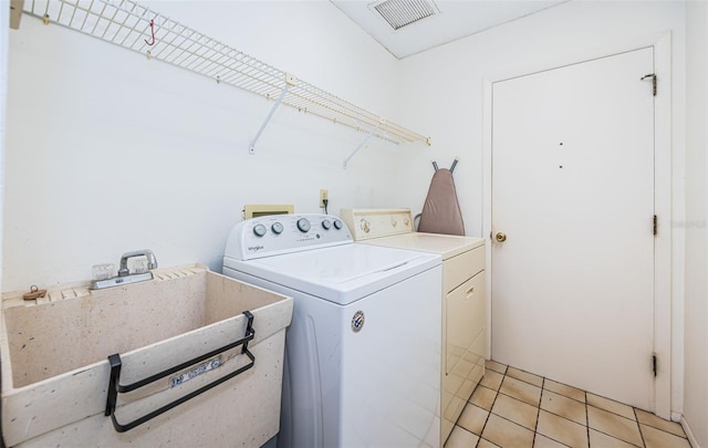 washroom with visible vents, a sink, separate washer and dryer, light tile patterned floors, and laundry area