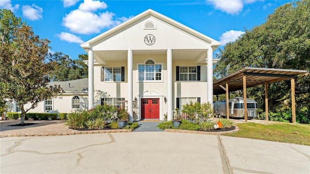 neoclassical home featuring a carport