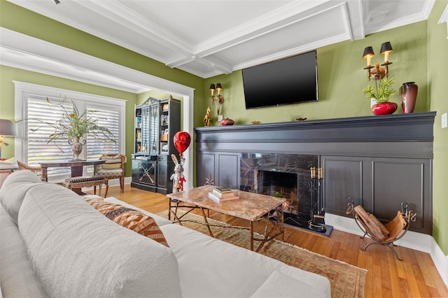 living room with a premium fireplace, crown molding, beam ceiling, and wood-type flooring