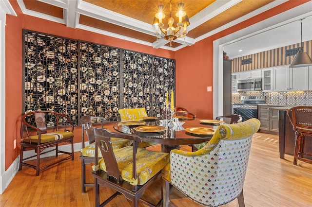 dining room with ornamental molding, a chandelier, light wood-type flooring, and a raised ceiling