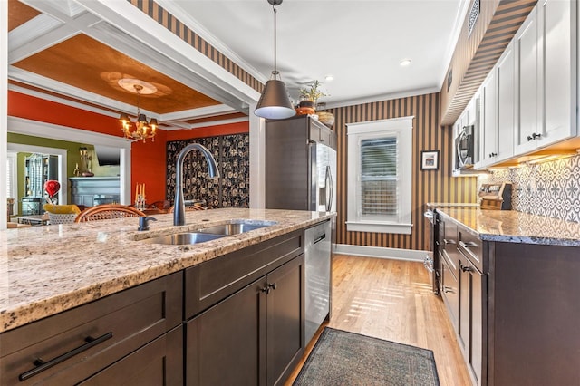 kitchen featuring sink, dark brown cabinets, hanging light fixtures, light hardwood / wood-style floors, and stainless steel appliances