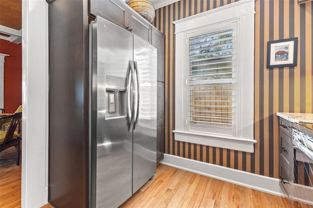 kitchen with appliances with stainless steel finishes, light stone counters, and light hardwood / wood-style floors