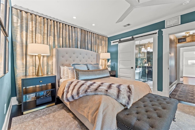 bedroom with ceiling fan, ornamental molding, and a barn door