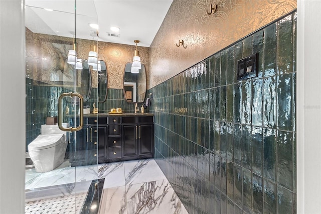 bathroom with tile walls, vanity, toilet, and an enclosed shower