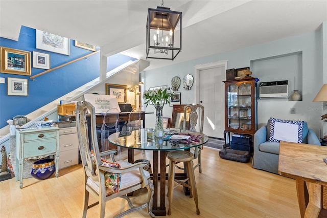 dining area featuring light hardwood / wood-style floors, a notable chandelier, and a wall mounted air conditioner