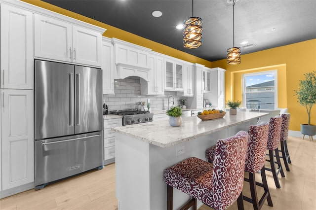 kitchen featuring a breakfast bar, white cabinetry, stainless steel appliances, and hanging light fixtures