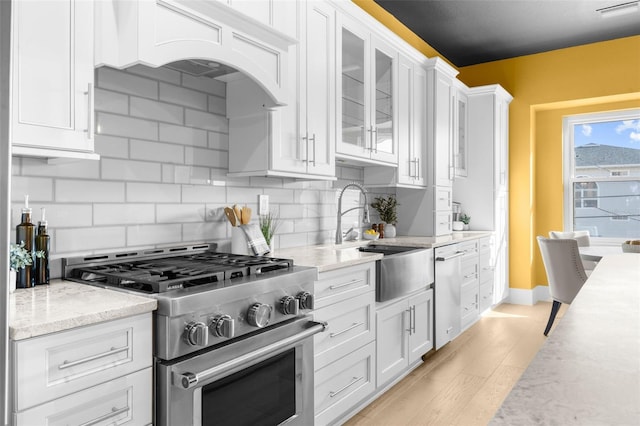 kitchen featuring white cabinetry, appliances with stainless steel finishes, light hardwood / wood-style flooring, and decorative backsplash