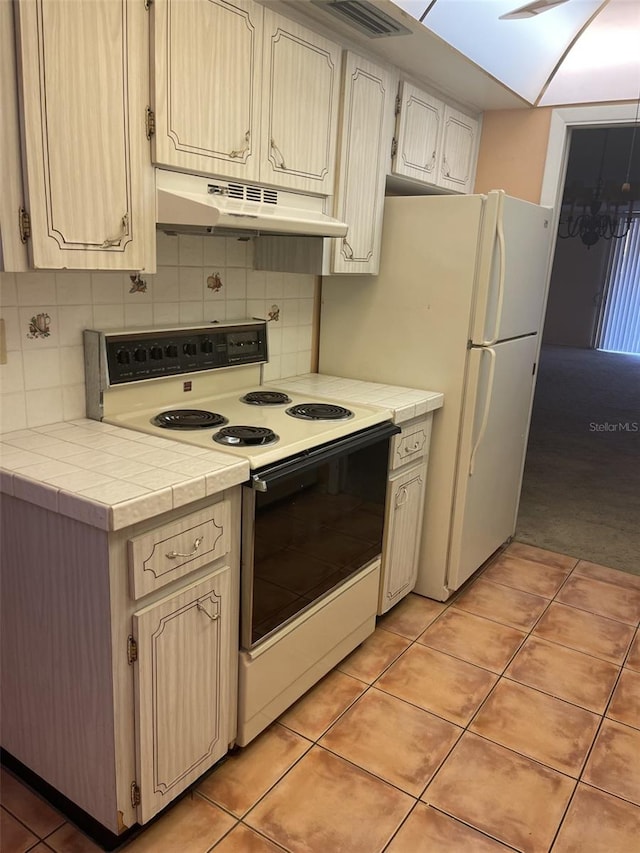 kitchen with tile countertops, white electric range, backsplash, and light tile patterned floors