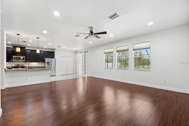 unfurnished living room featuring ceiling fan, a textured ceiling, sink, and dark hardwood / wood-style flooring