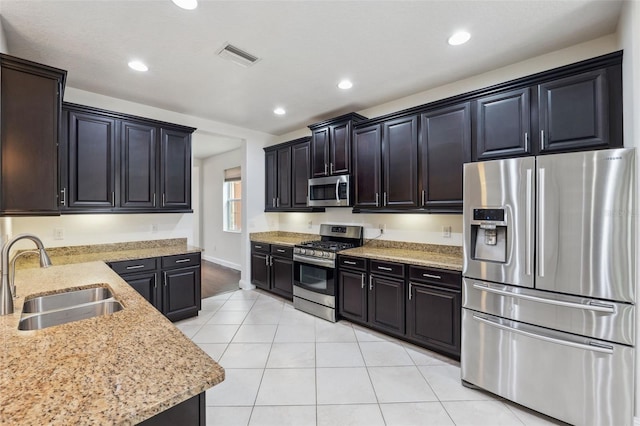 kitchen with light tile patterned flooring, sink, light stone counters, and appliances with stainless steel finishes