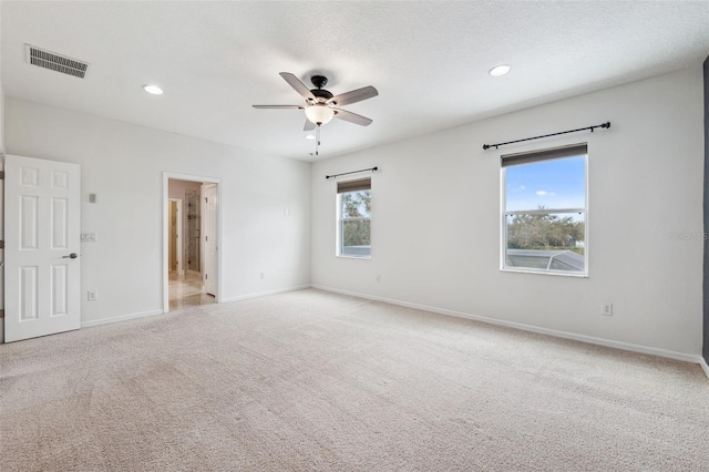 carpeted spare room featuring plenty of natural light and ceiling fan