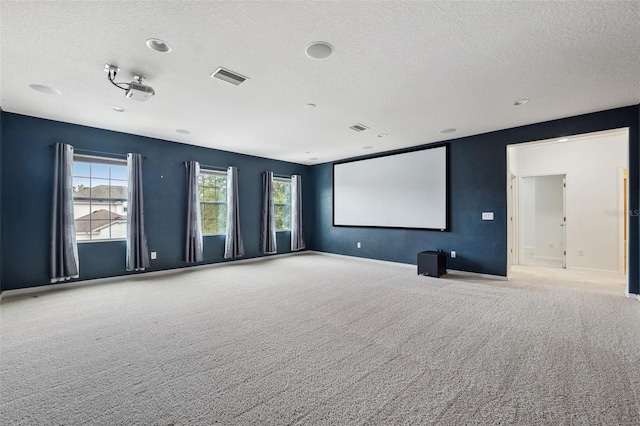 home theater room with a textured ceiling and light carpet