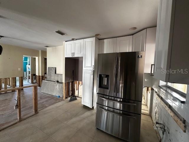 kitchen featuring stainless steel fridge and white cabinetry