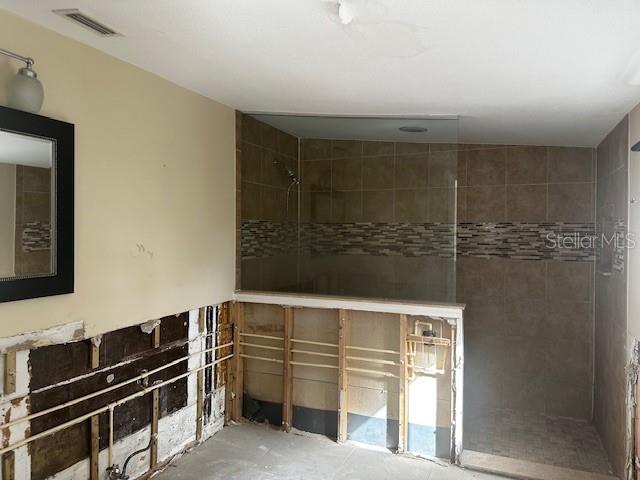 bathroom featuring tiled shower and concrete flooring