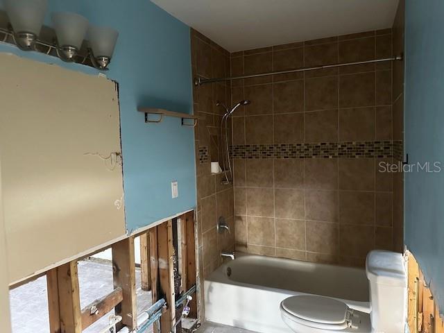 bathroom featuring toilet and tiled shower / bath