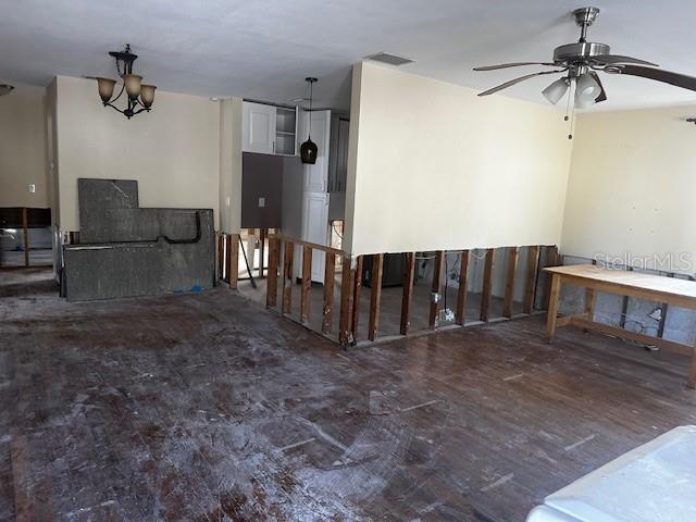 spare room featuring ceiling fan with notable chandelier