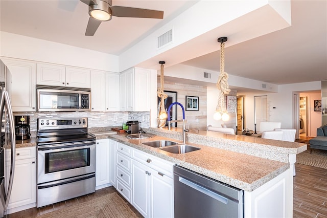 kitchen with appliances with stainless steel finishes, kitchen peninsula, dark hardwood / wood-style floors, and white cabinets