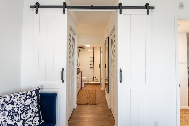 corridor with a barn door and hardwood / wood-style flooring