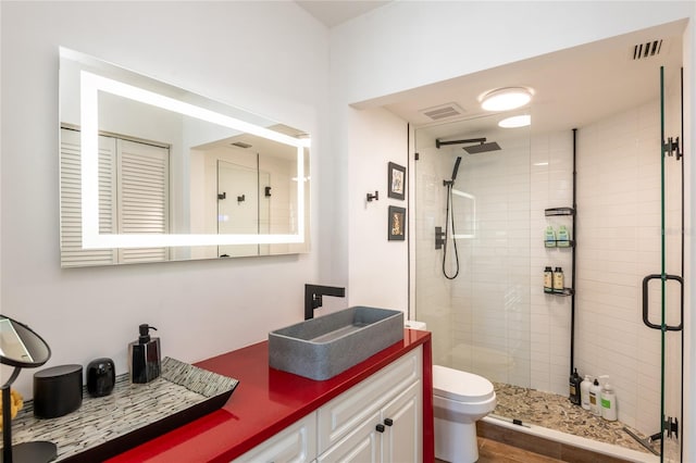 bathroom with vanity, toilet, and a shower with door