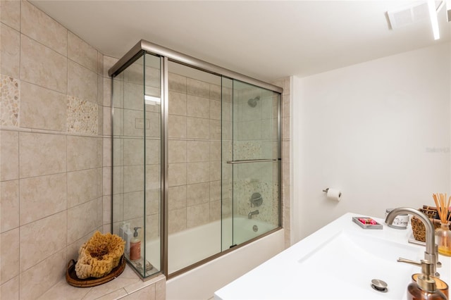 bathroom featuring combined bath / shower with glass door and sink