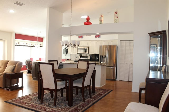 dining space featuring a high ceiling, a notable chandelier, and wood-type flooring