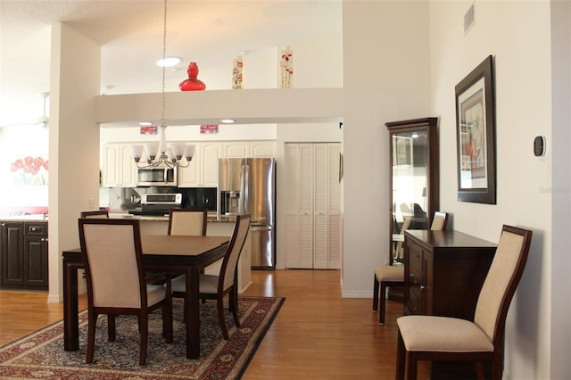 dining area with an inviting chandelier, dark wood-type flooring, and a high ceiling