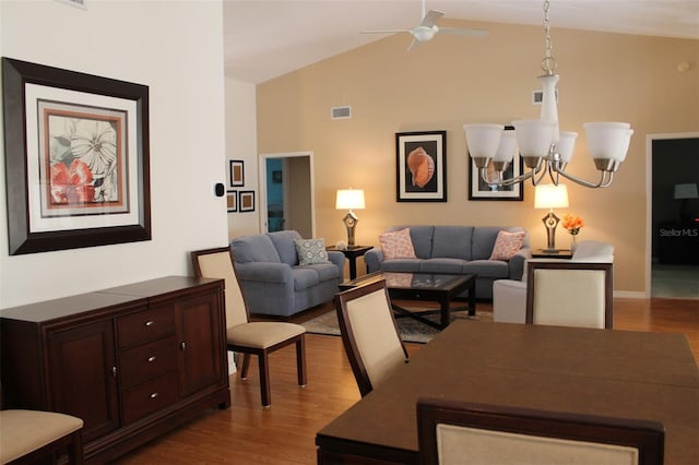 living room featuring high vaulted ceiling, ceiling fan with notable chandelier, and light hardwood / wood-style floors