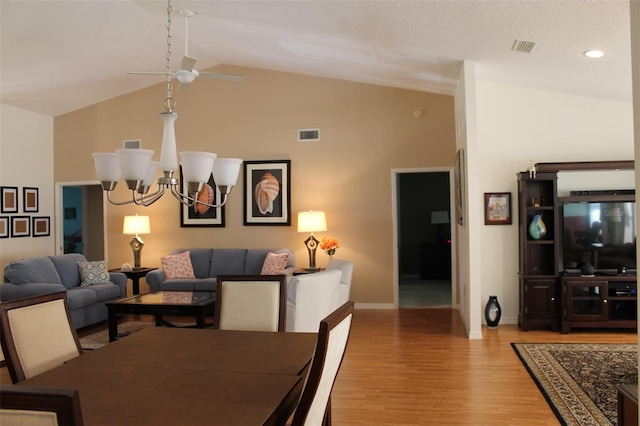 dining room featuring a textured ceiling, hardwood / wood-style flooring, high vaulted ceiling, and ceiling fan with notable chandelier