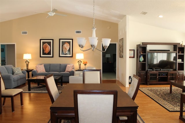 dining room featuring high vaulted ceiling, ceiling fan with notable chandelier, and hardwood / wood-style floors